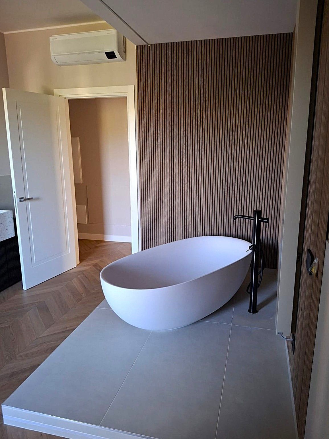 Bagno moderno con pavimento effetto legno, doppio lavabo, doccia, WC e bidet.