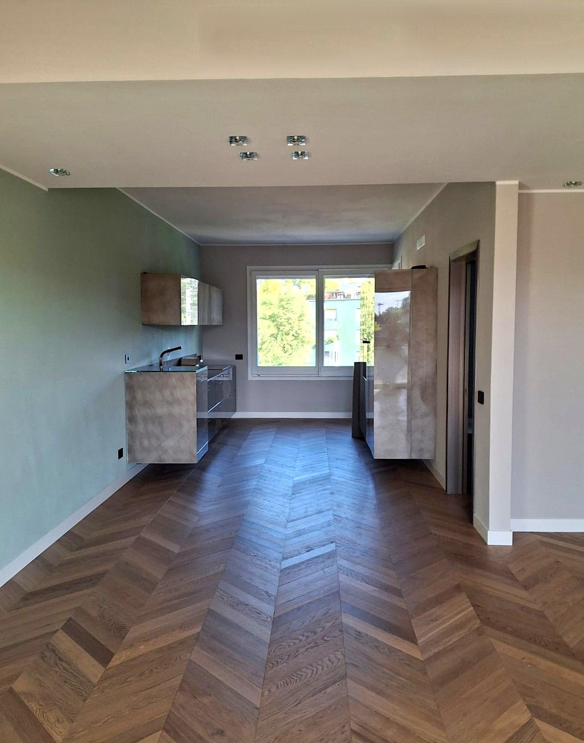 Cucina moderna con mobili grigi, elettrodomestici in acciaio inossidabile e piano cottura.
