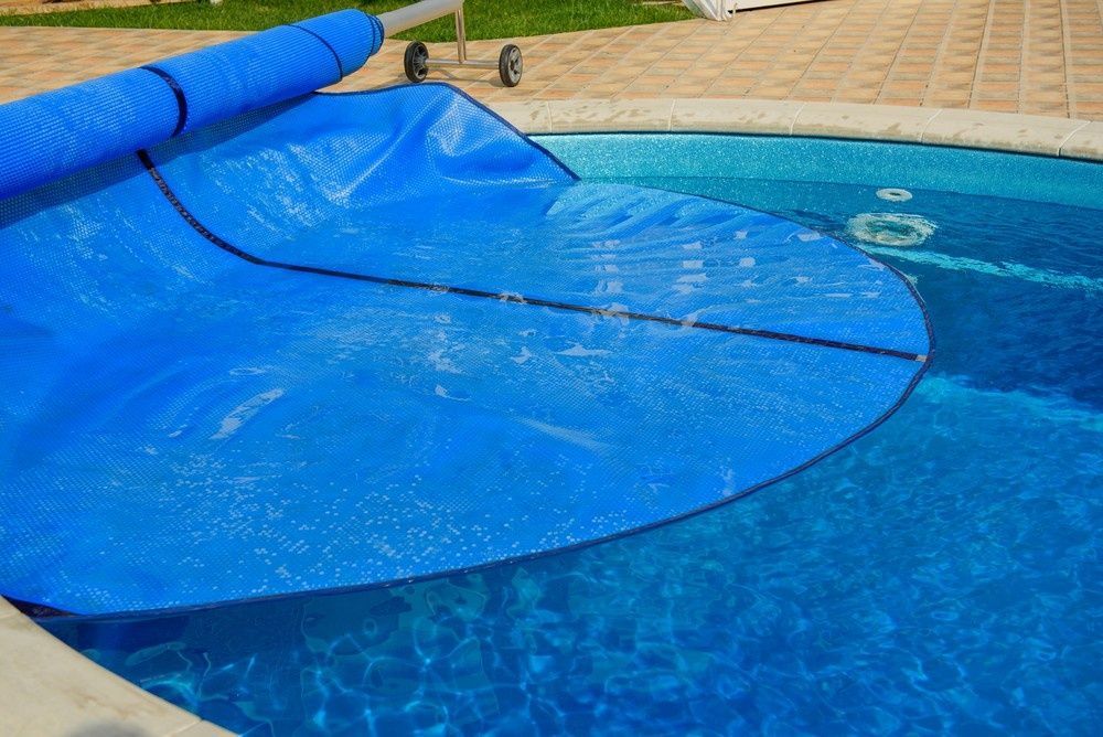 Blue Pool Cover Partially Covering a Round Pool. the Cover Is Rolled on A Spool — Ultra Clear Pool Care in Cranbrook, QLD