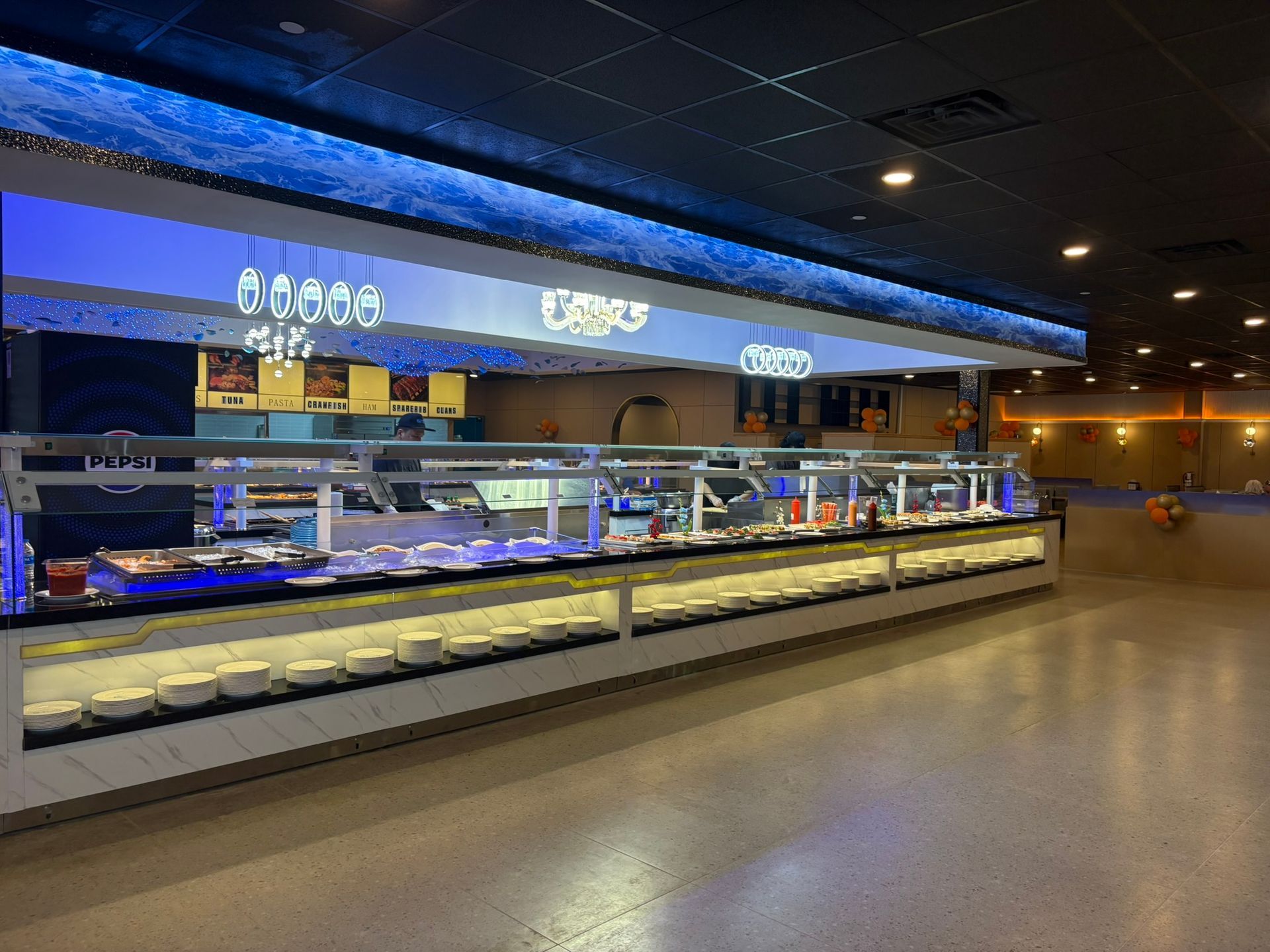 Empty sushi buffet counter with lit display cases and blue signage in a modern restaurant