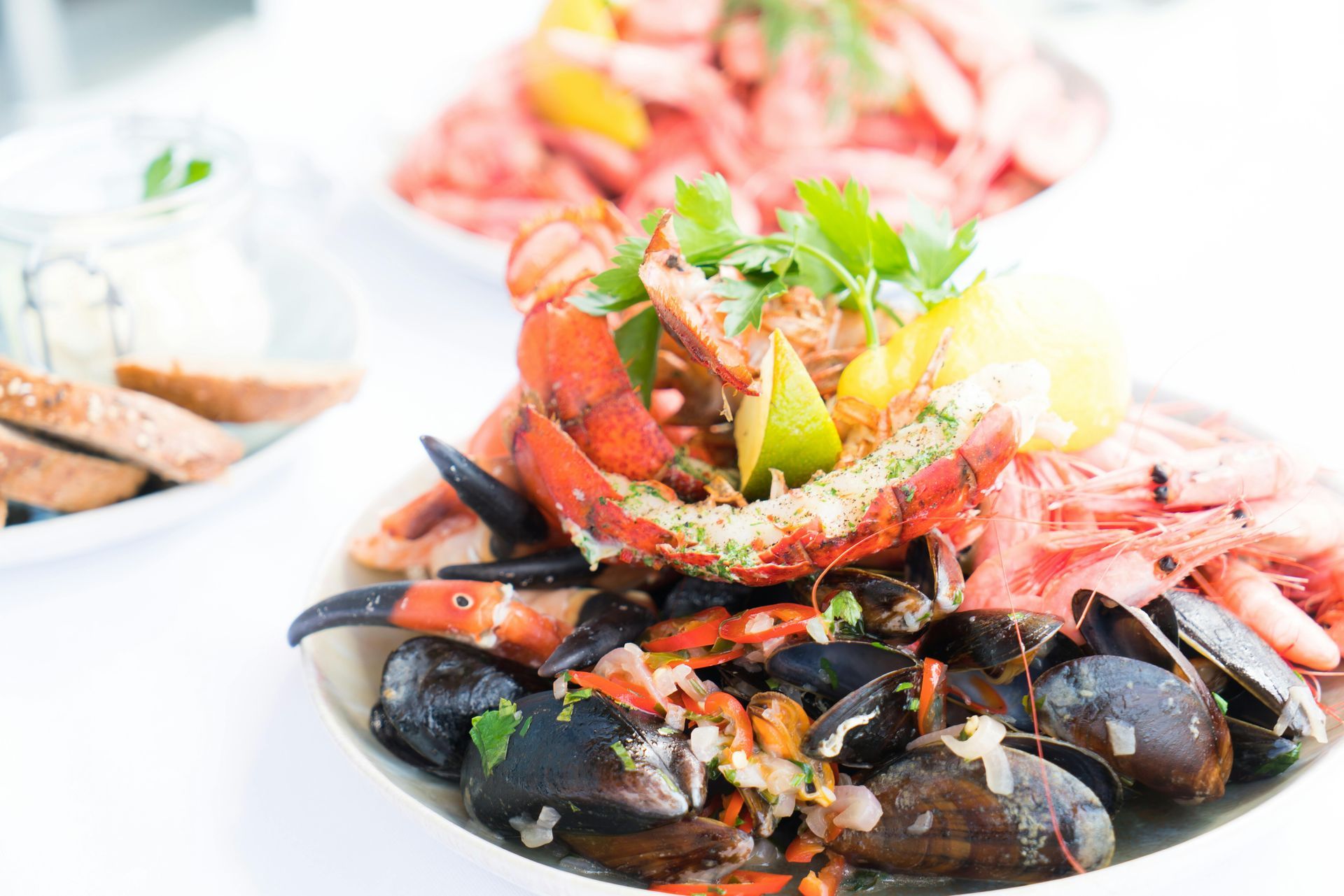 Seafood platter with lobster, mussels, and garnishes on a white plate