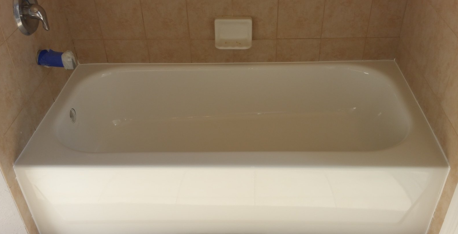A white bathtub is sitting in a bathroom next to a tiled wall.