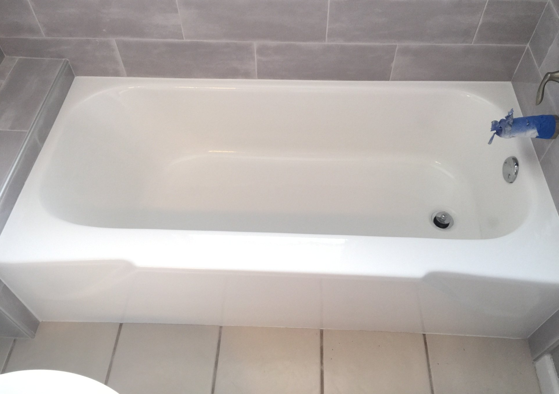 A white bathtub in a bathroom next to a toilet.