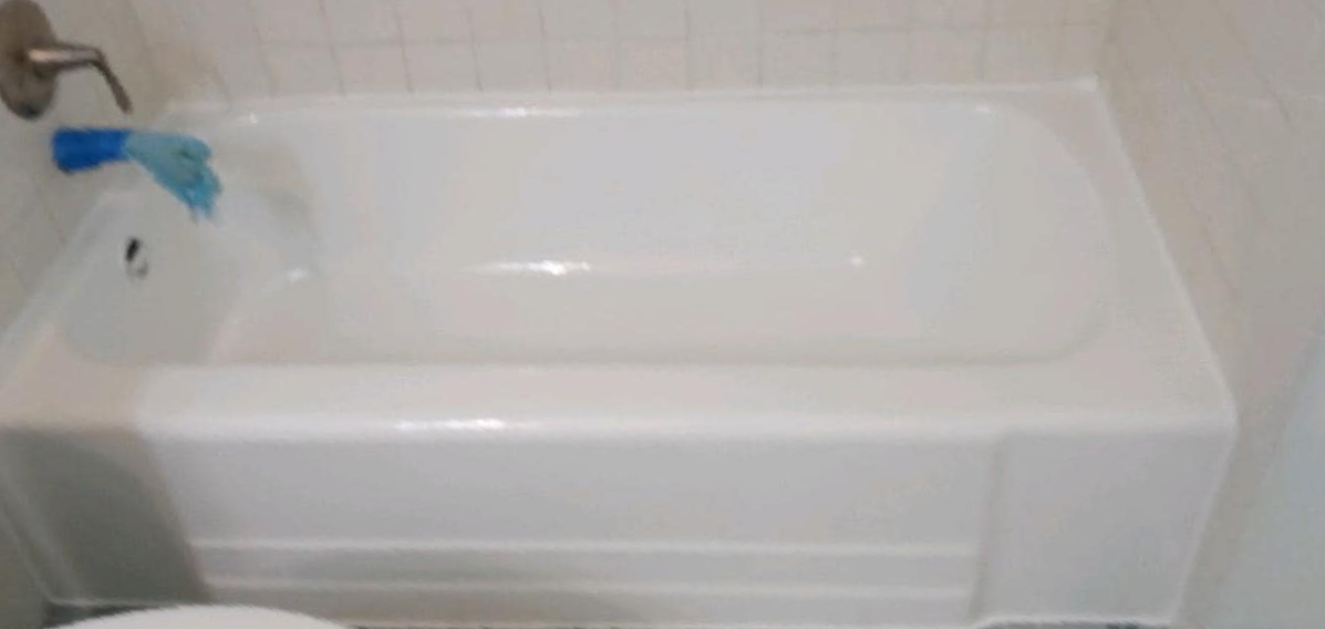 A white bathtub in a bathroom next to a toilet.
