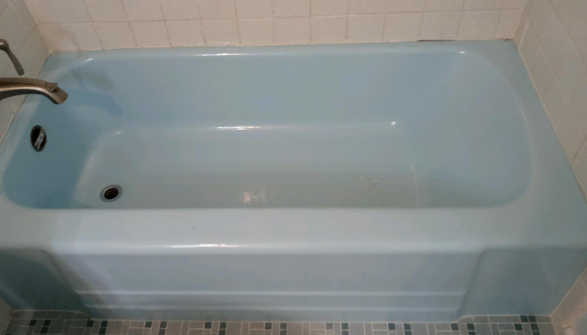 A blue bathtub with a faucet in a bathroom.