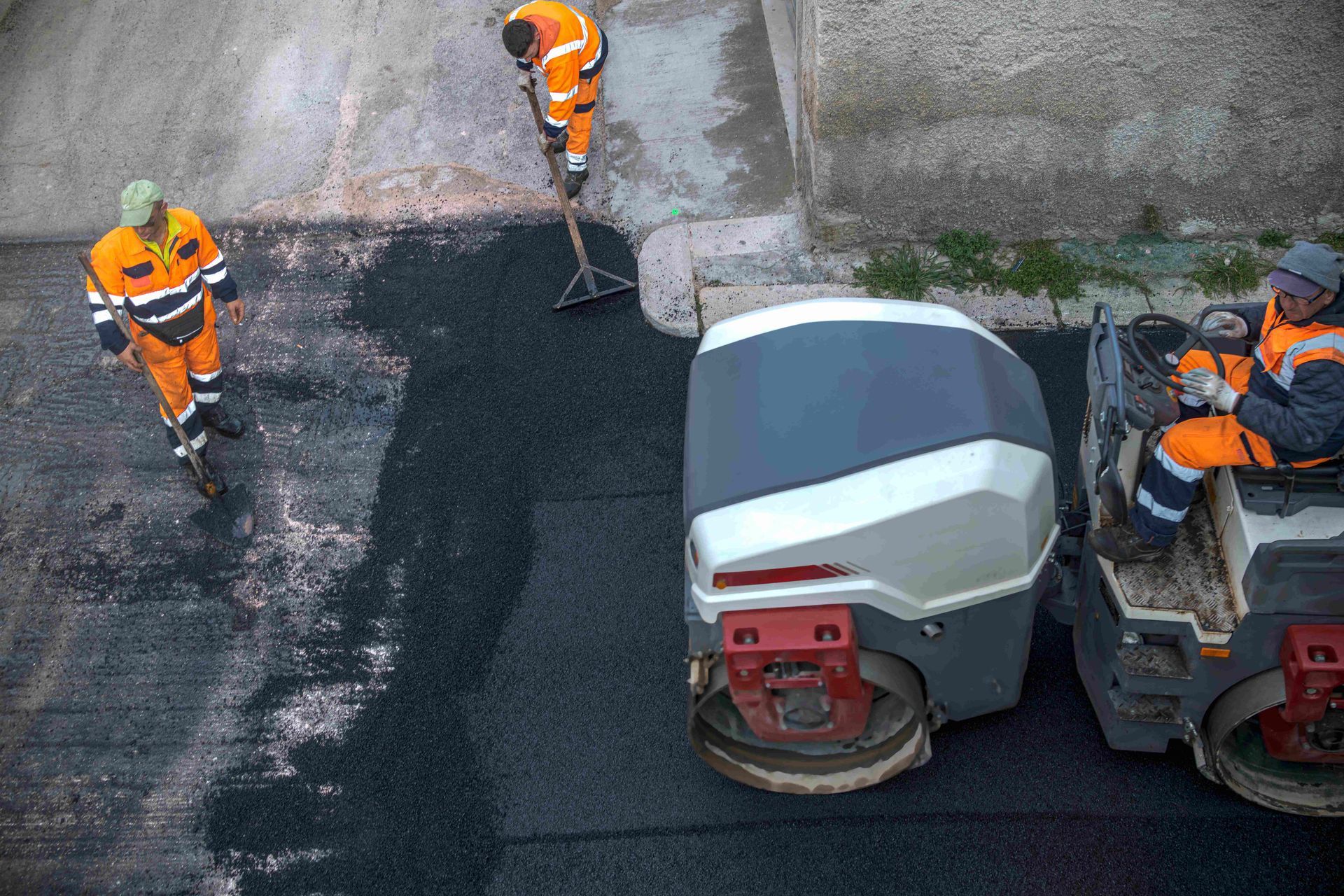 Asphalt paving crew operating compaction equipment and laying fresh asphalt during a commercial pavi