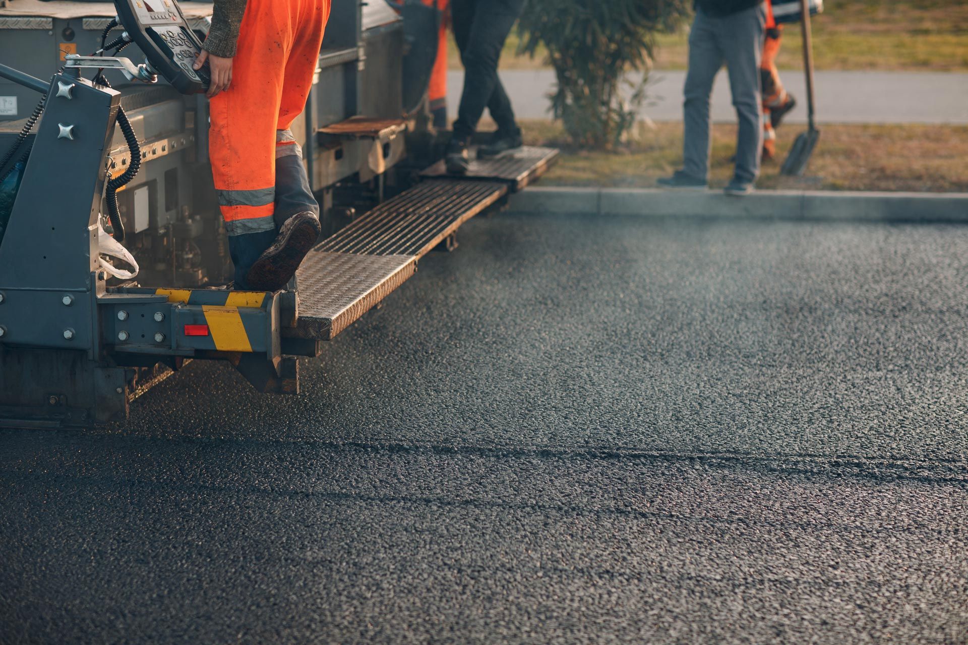 Road paving crew working with an asphalt paver on a freshly laid road