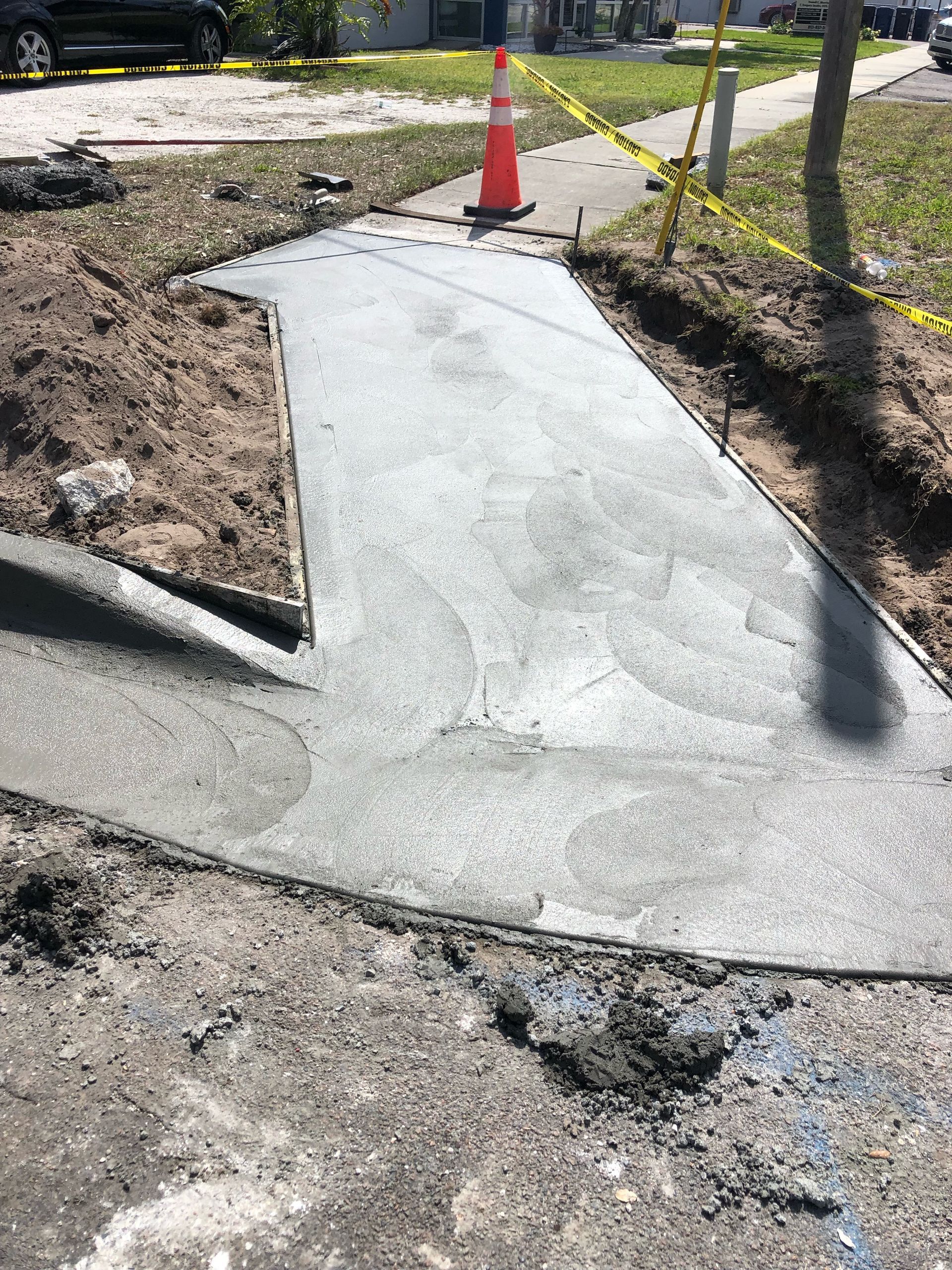 Concrete drainage ditch next to a gray road and dry, brown dirt.