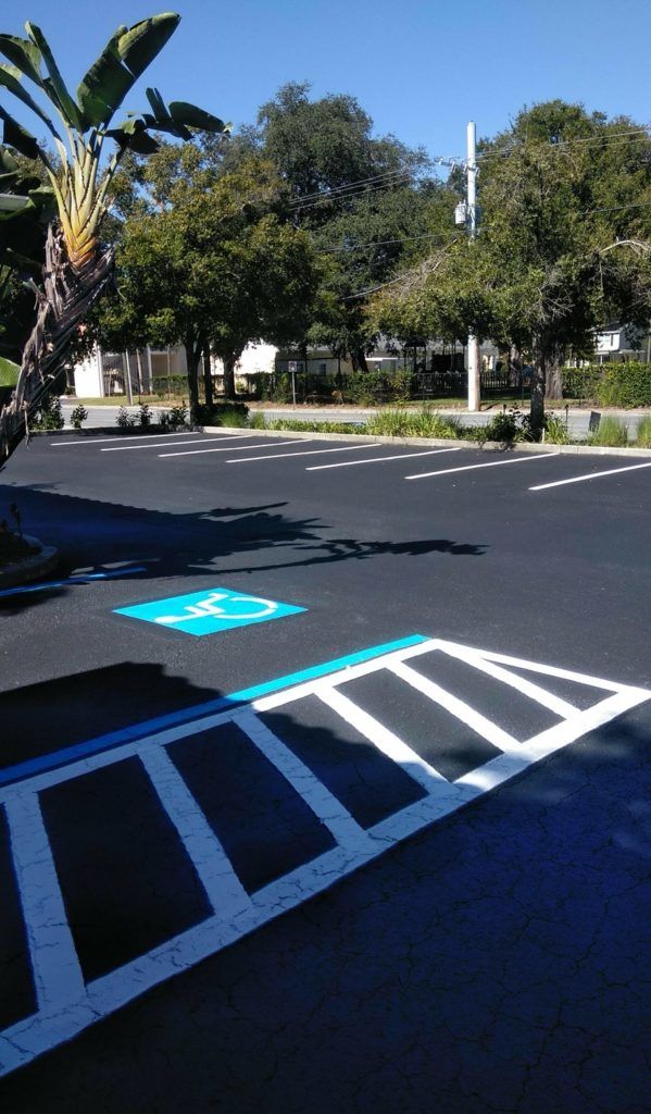 Empty parking lot with blue handicap symbol and access area, sunny day.