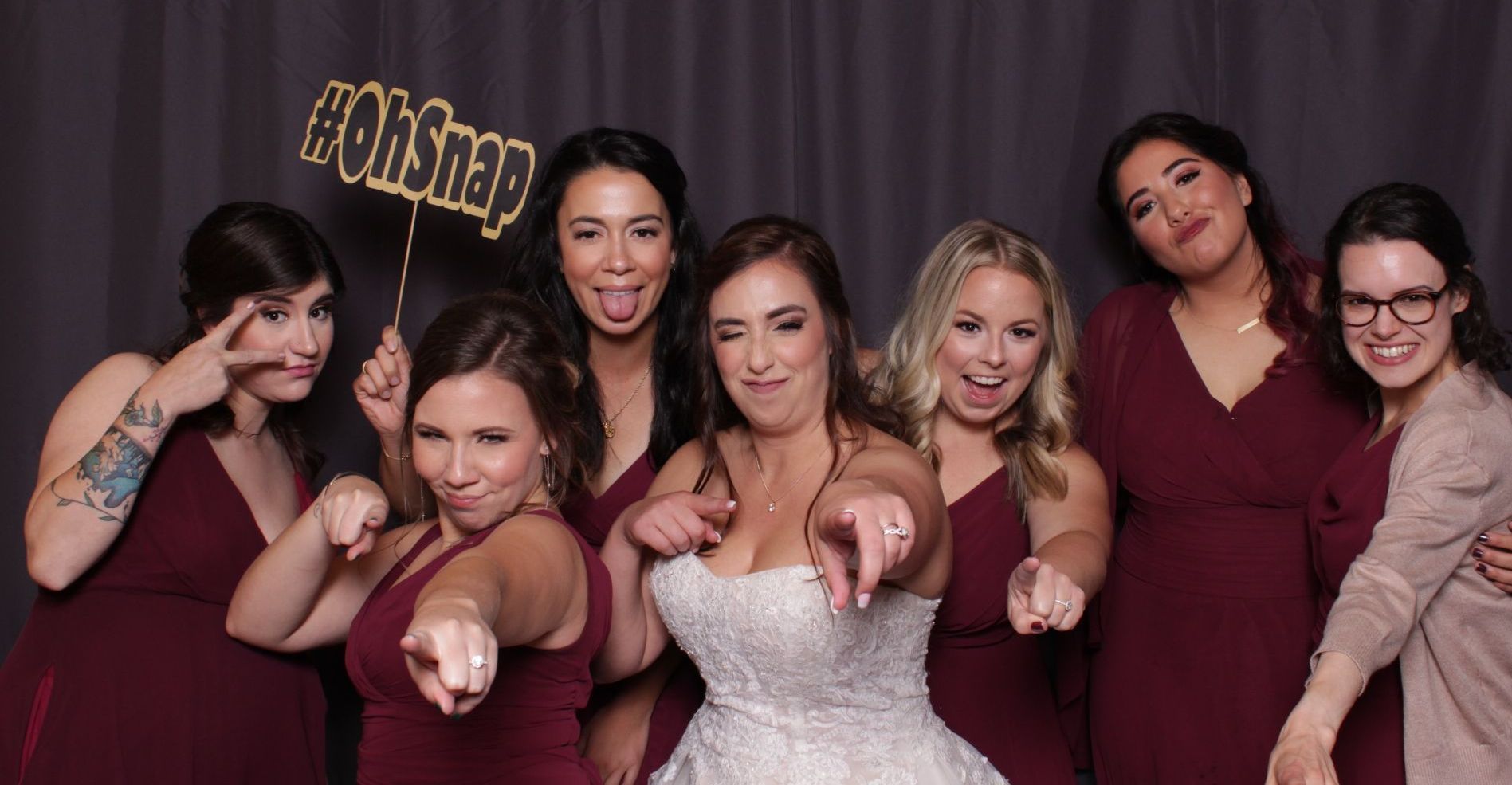 A bride and her bridesmaids are posing for a picture in a photo booth.