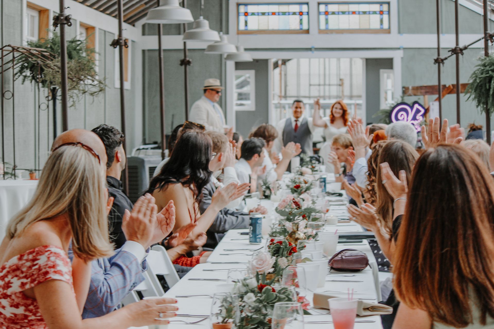 A group of people are sitting at a long table clapping their hands.