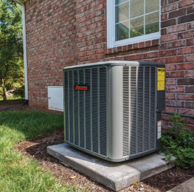 Technician inspecting a home air conditioner unit outside a house