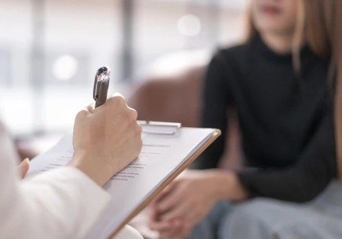 Therapist taking notes during a counseling session with a seated client indoors
