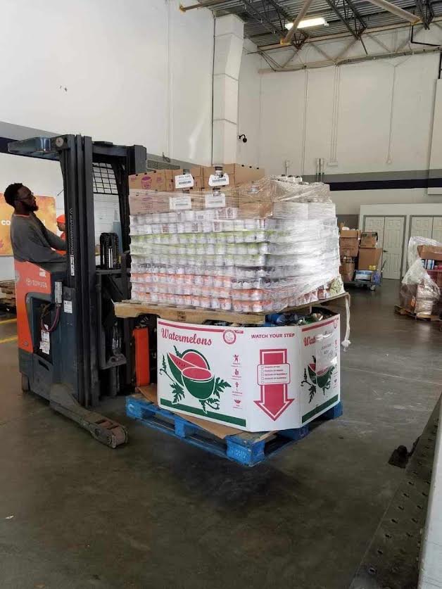 A forklift is carrying a pallet of food in a warehouse.