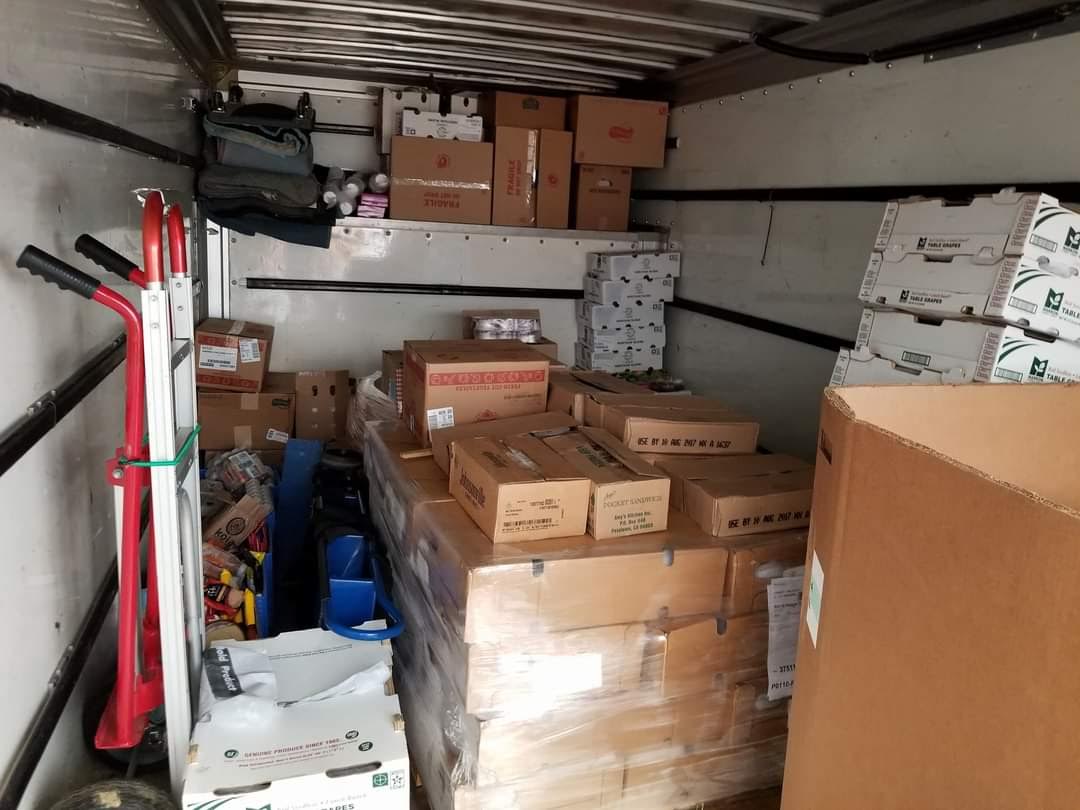 The inside of a moving truck filled with boxes and a dolly.