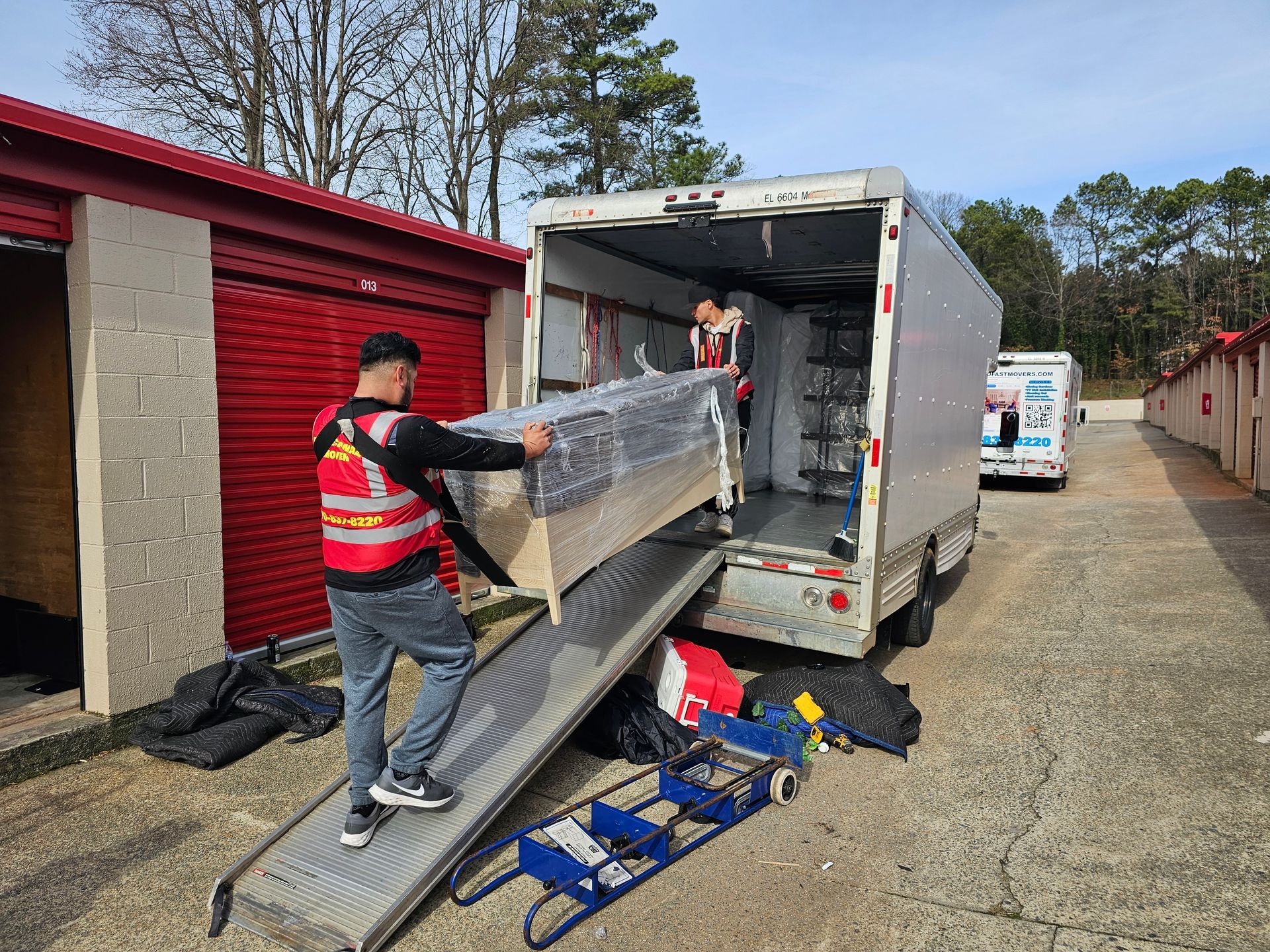 Two men are carrying a refrigerator up a set of stairs.