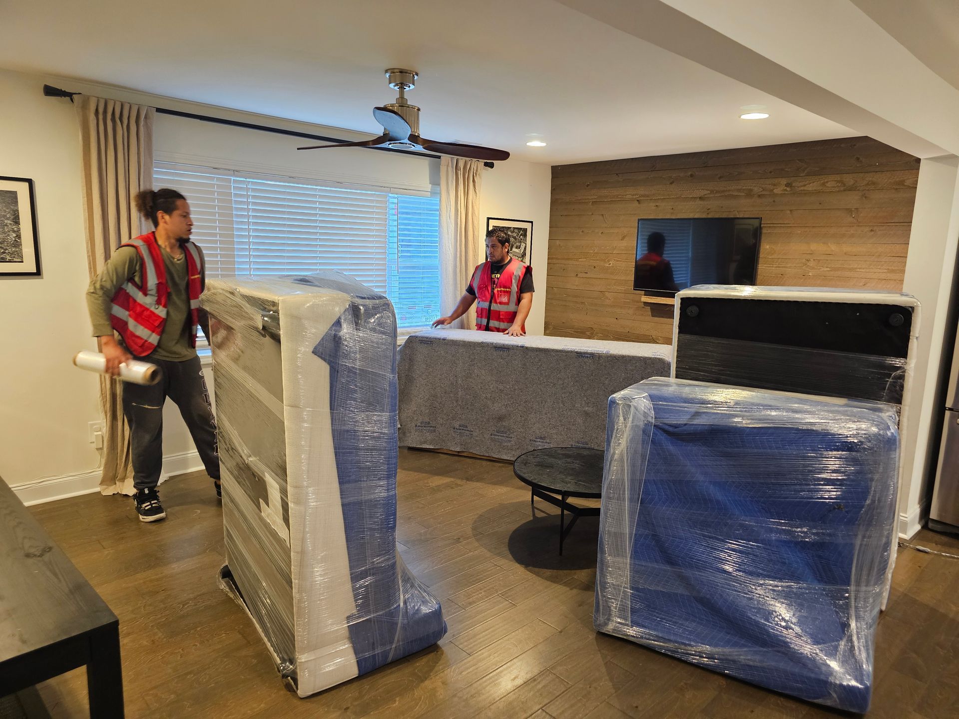 Two men are carrying a refrigerator up a set of stairs.