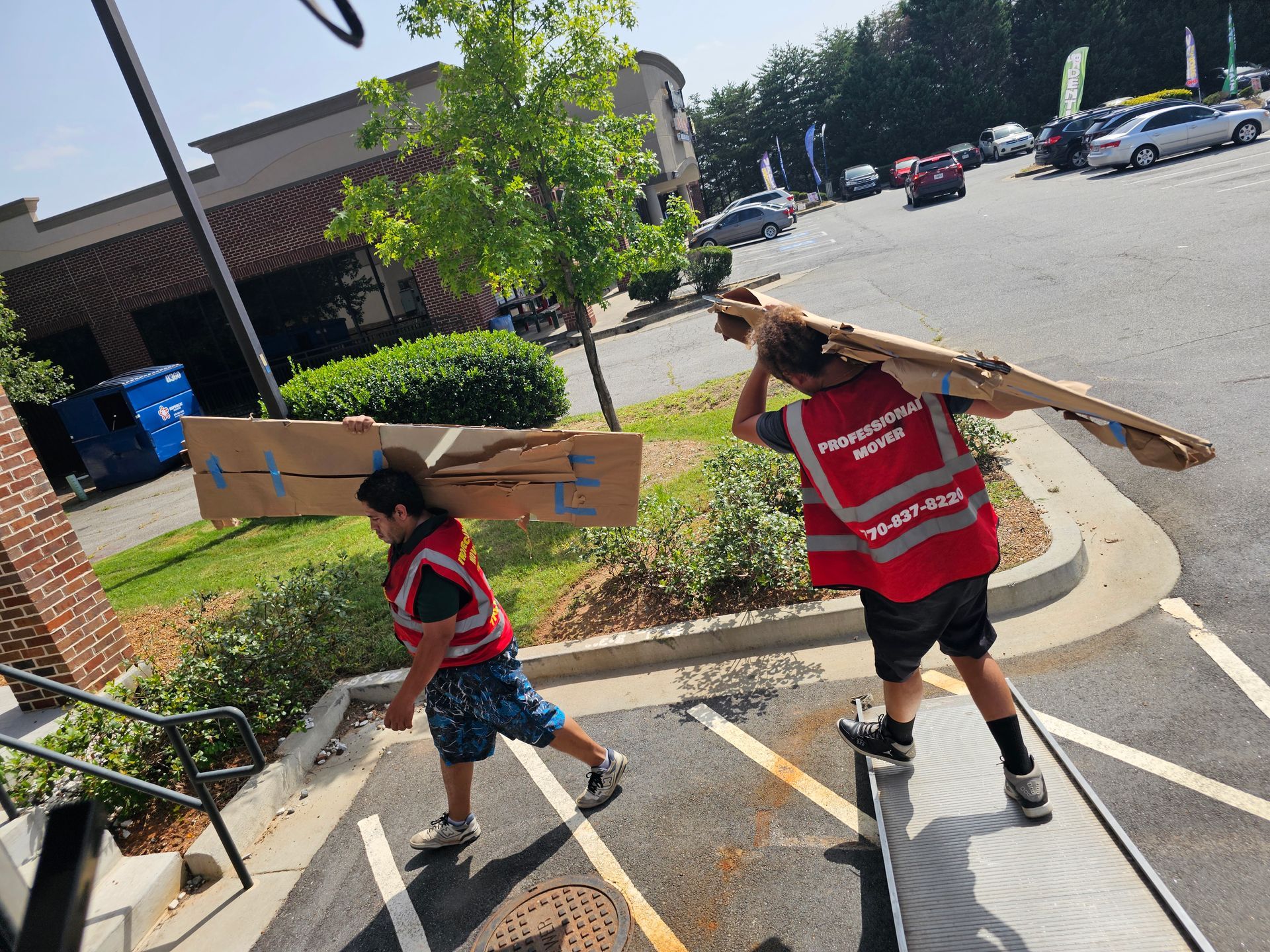 Two men are carrying a refrigerator up a set of stairs.