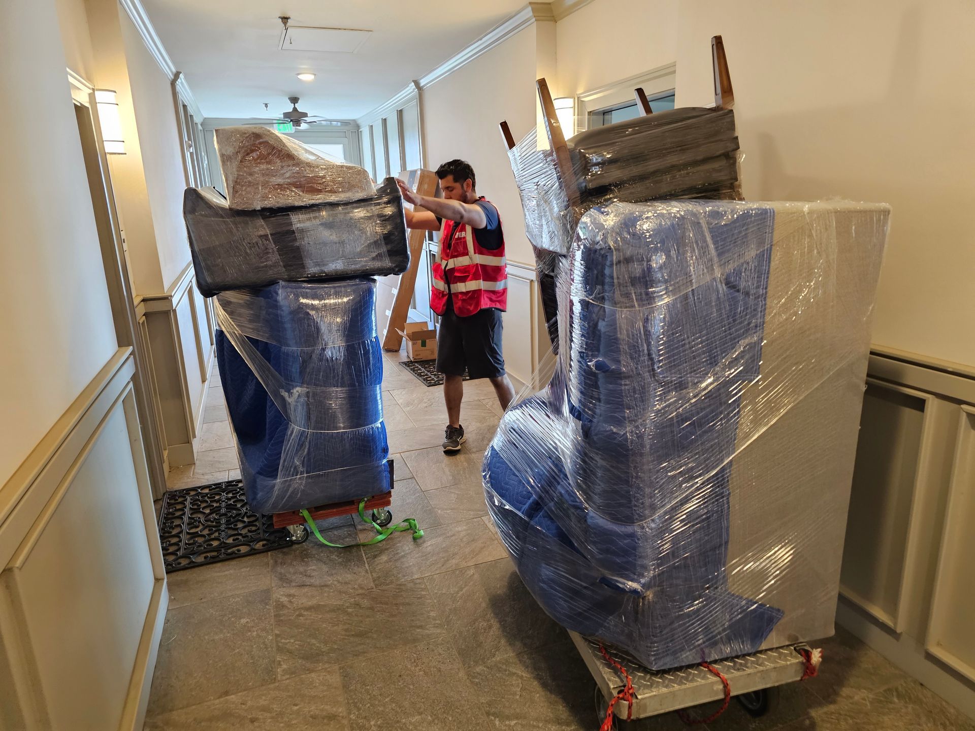 A man is wrapping a chair in plastic wrap in a living room.