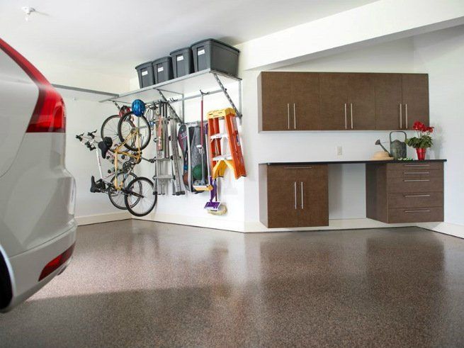 A car is parked in a garage with a bicycle hanging on the wall.
