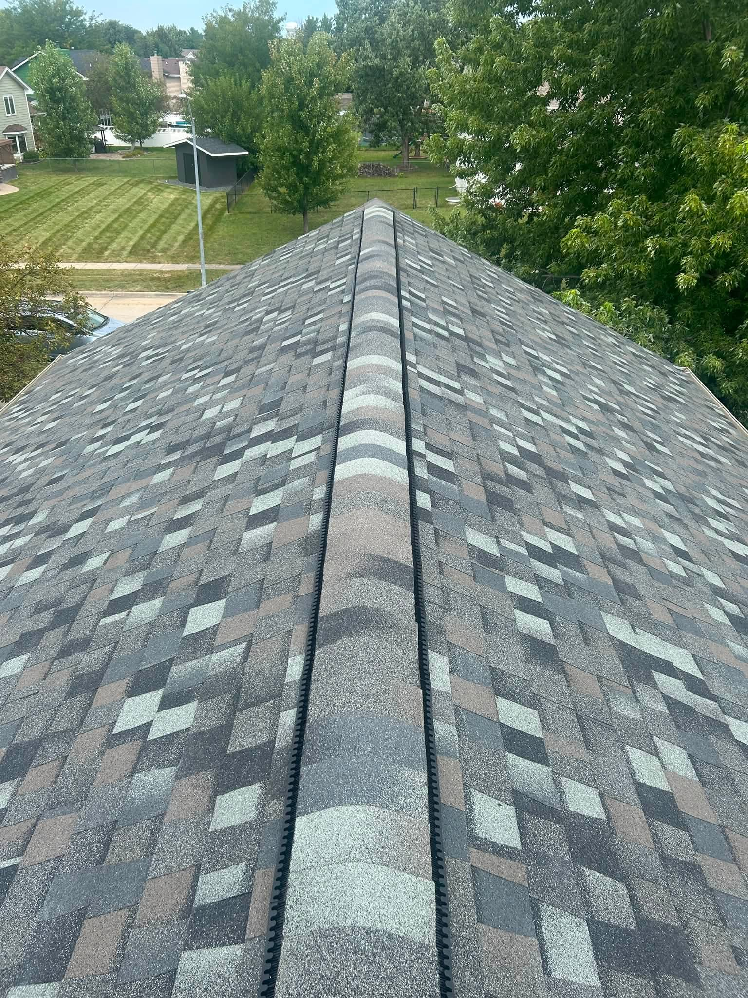 Two roofers in safety vests and hard hats installing tiles on a roof.