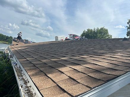 Close-up of new architectural shingle roof with roofing crew in background.