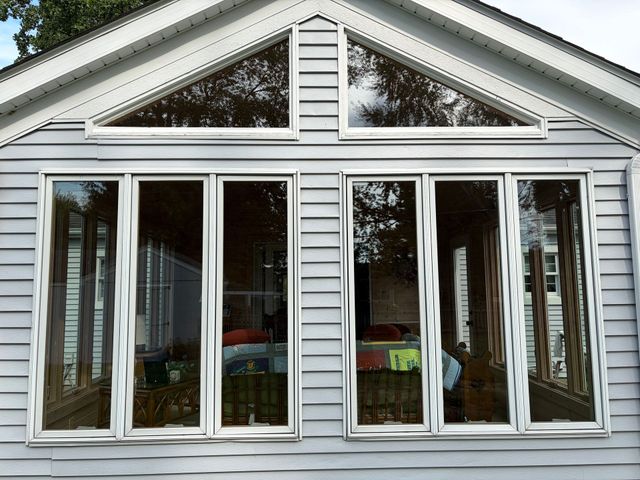 White house sunroom with large sliding glass doors and a peaked gable window