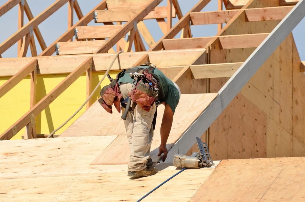A Man Is Working on The Roof of A House — Trussframe in Armidale, NSW