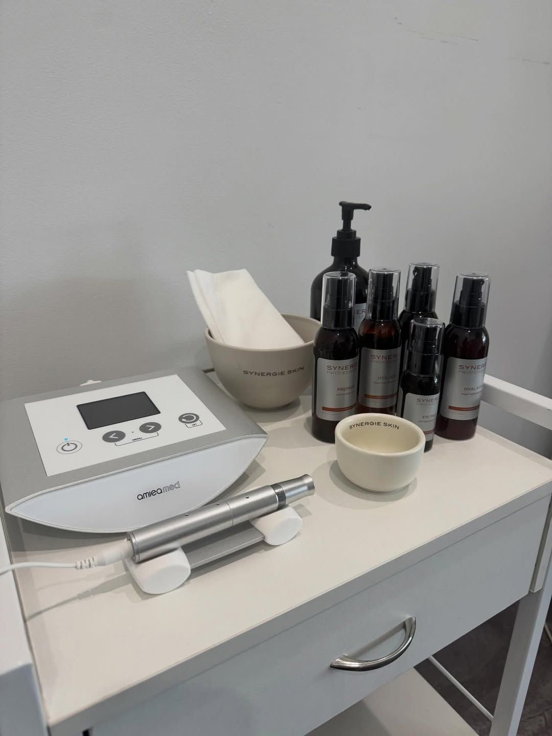 A professional beauty treatment station featuring a facial device with a handpiece, several skincare bottles, and bowls — Skin Haven Aesthetics Whitsundays in Airlie Beach, QLD