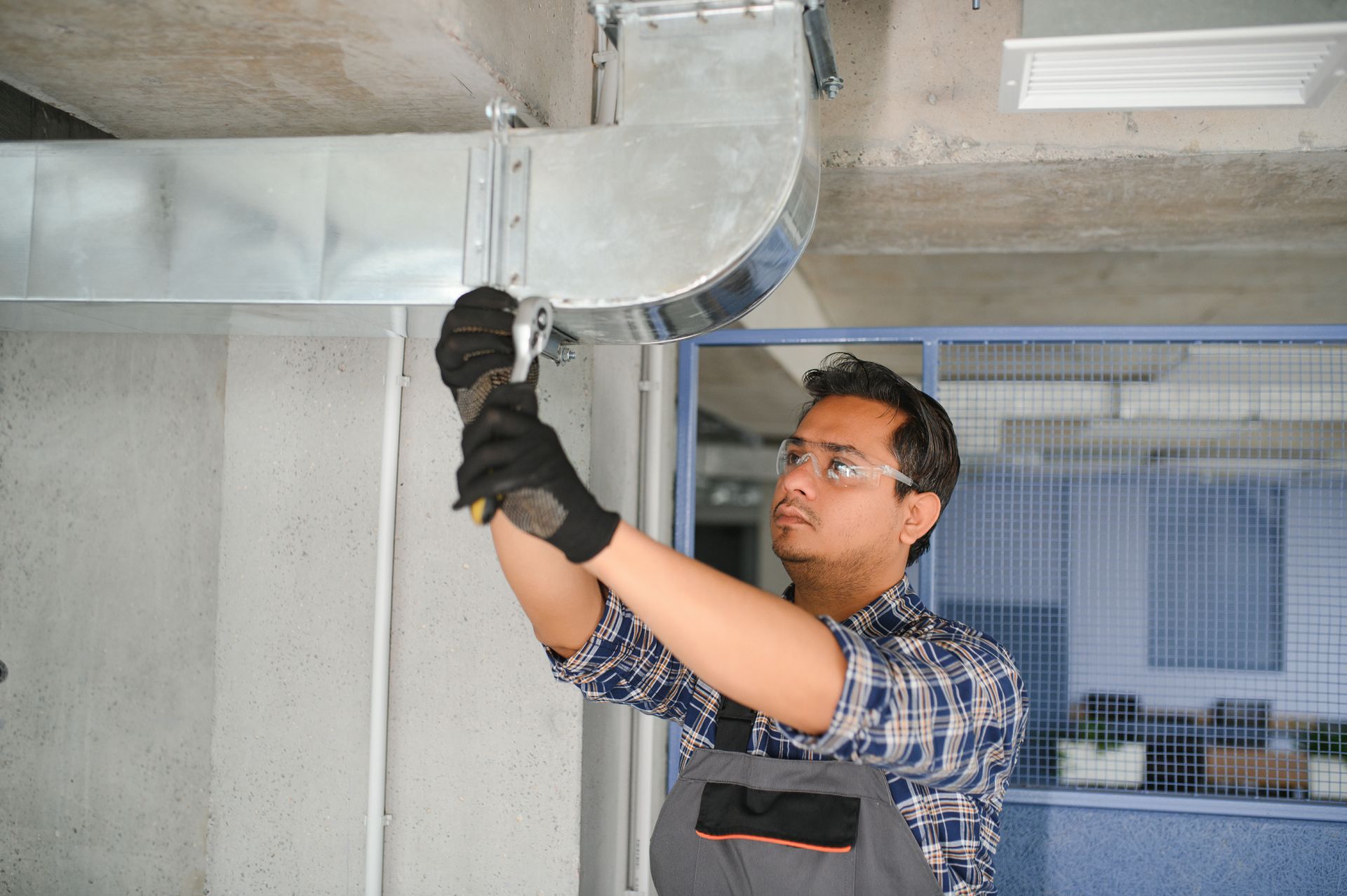 A man is working on a metal pipe with a wrench.