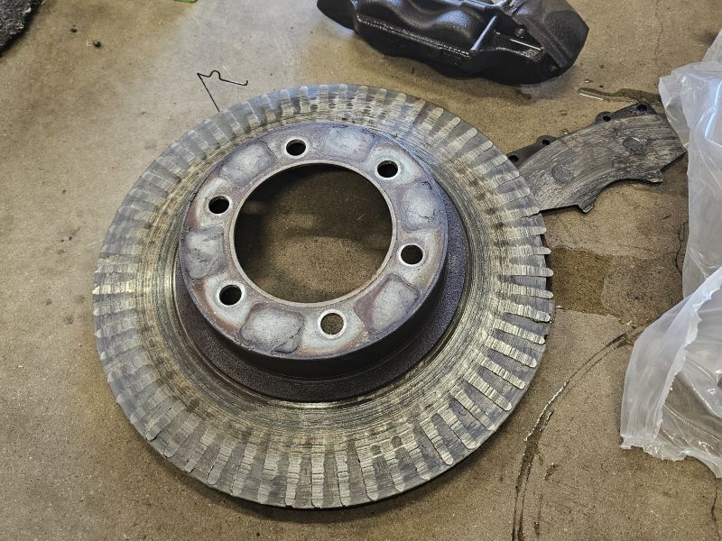 Mechanic inspecting worn brake rotor at Quicker Sticker College Station