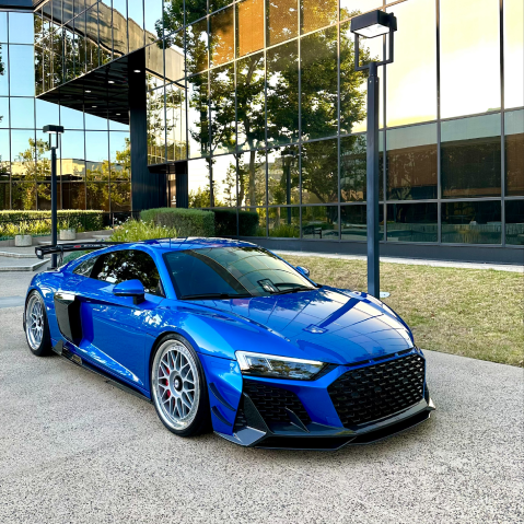 Blue sports car parked outside a glass office building on a sunny day | Pacific Germany