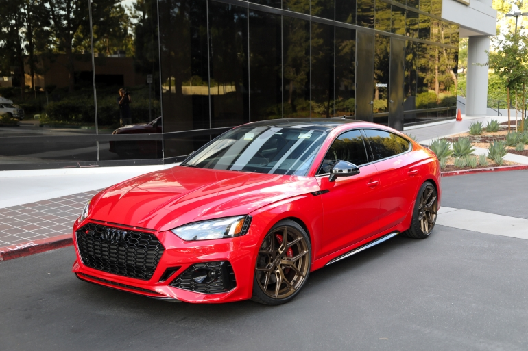 Red sports coupe parked outside a glass-fronted buildingSilver and neon yellow sports car with oversized rear wing parked beside a white wall. | Pacific German