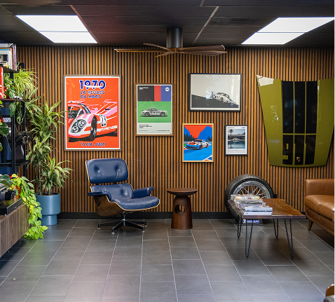 Retro-style lounge with blue chair, wood-paneled walls, vintage posters, and a tire table display | Pacific German