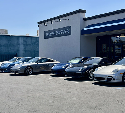 Parked sports cars outside a Porsche dealership on a sunny day | Pacific German