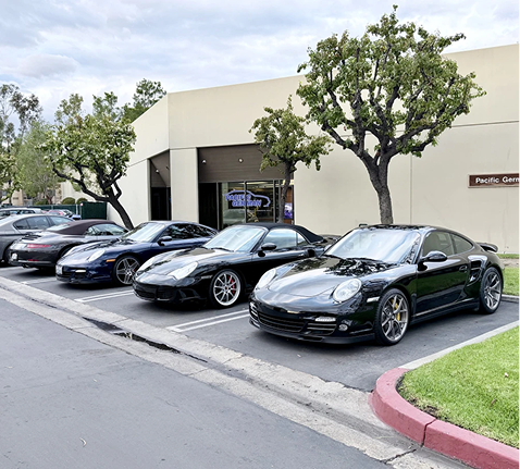Parked sports cars outside a Porsche dealership on a sunny day | Pacific German