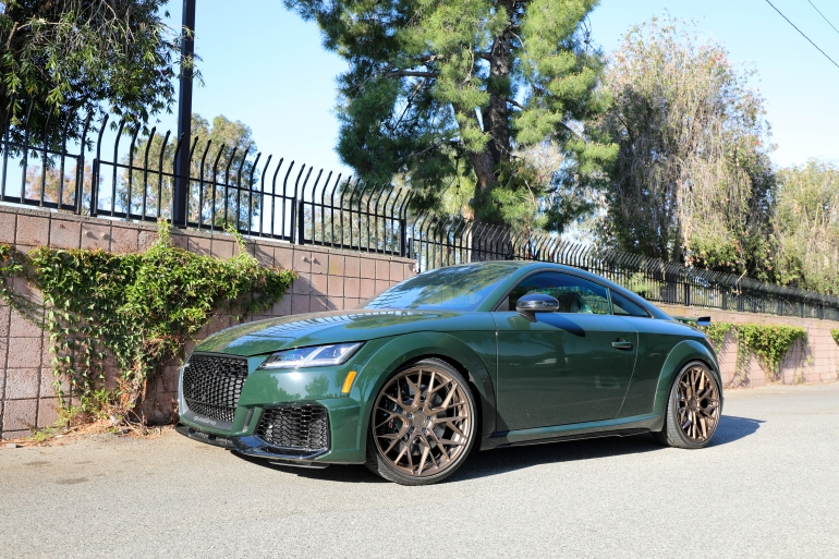 Green sports coupe parked on a sunny street beside a brick wall and iron fenceSilver and neon yellow sports car with oversized rear wing parked beside a white wall. | Pacific German