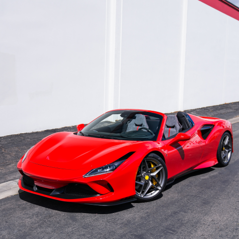 Red Ferrari convertible parked beside a white wall on a sunny street | Pacific Germany