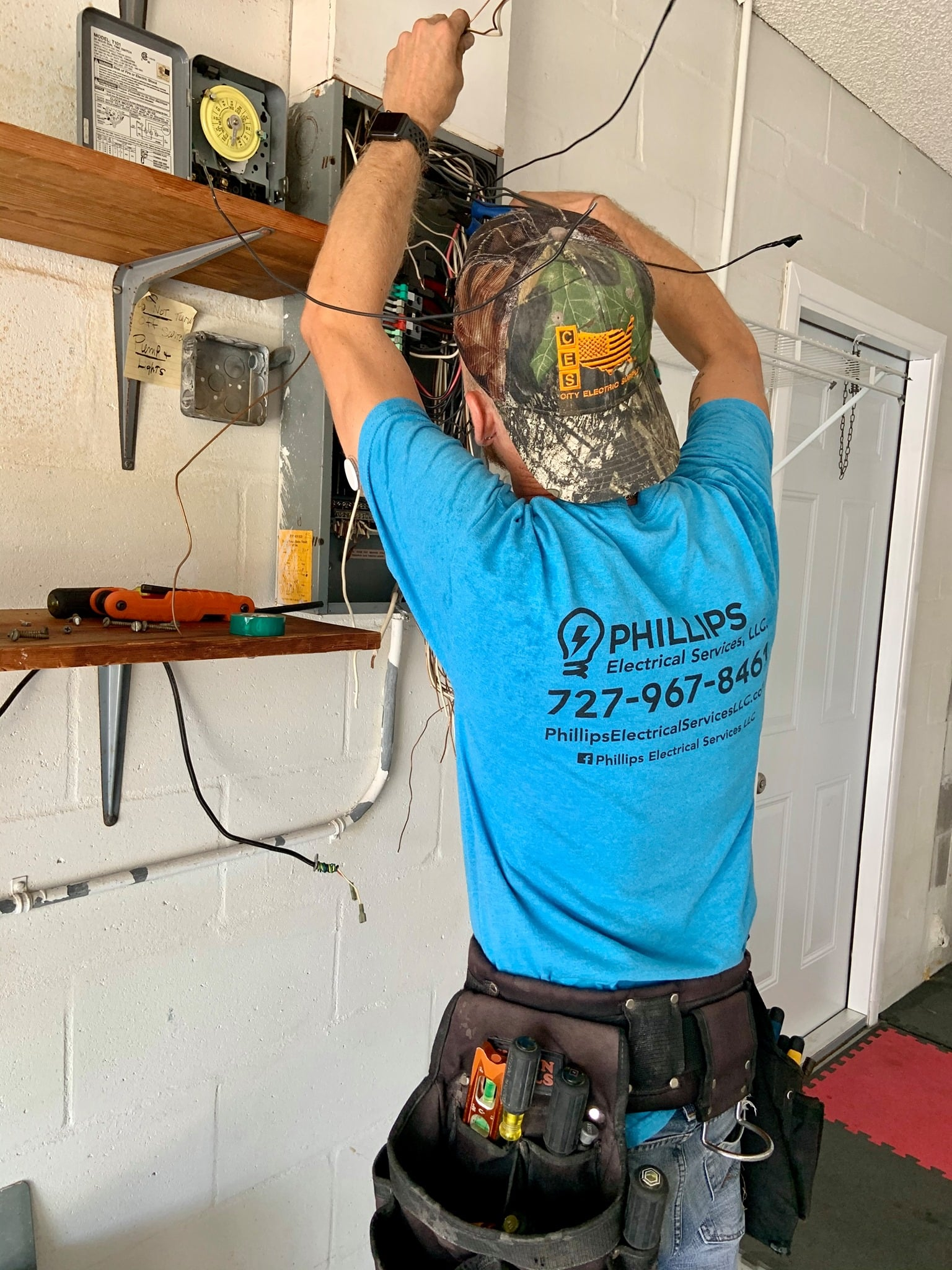 Person wiring a wall outlet with tools and colored electrical wires.