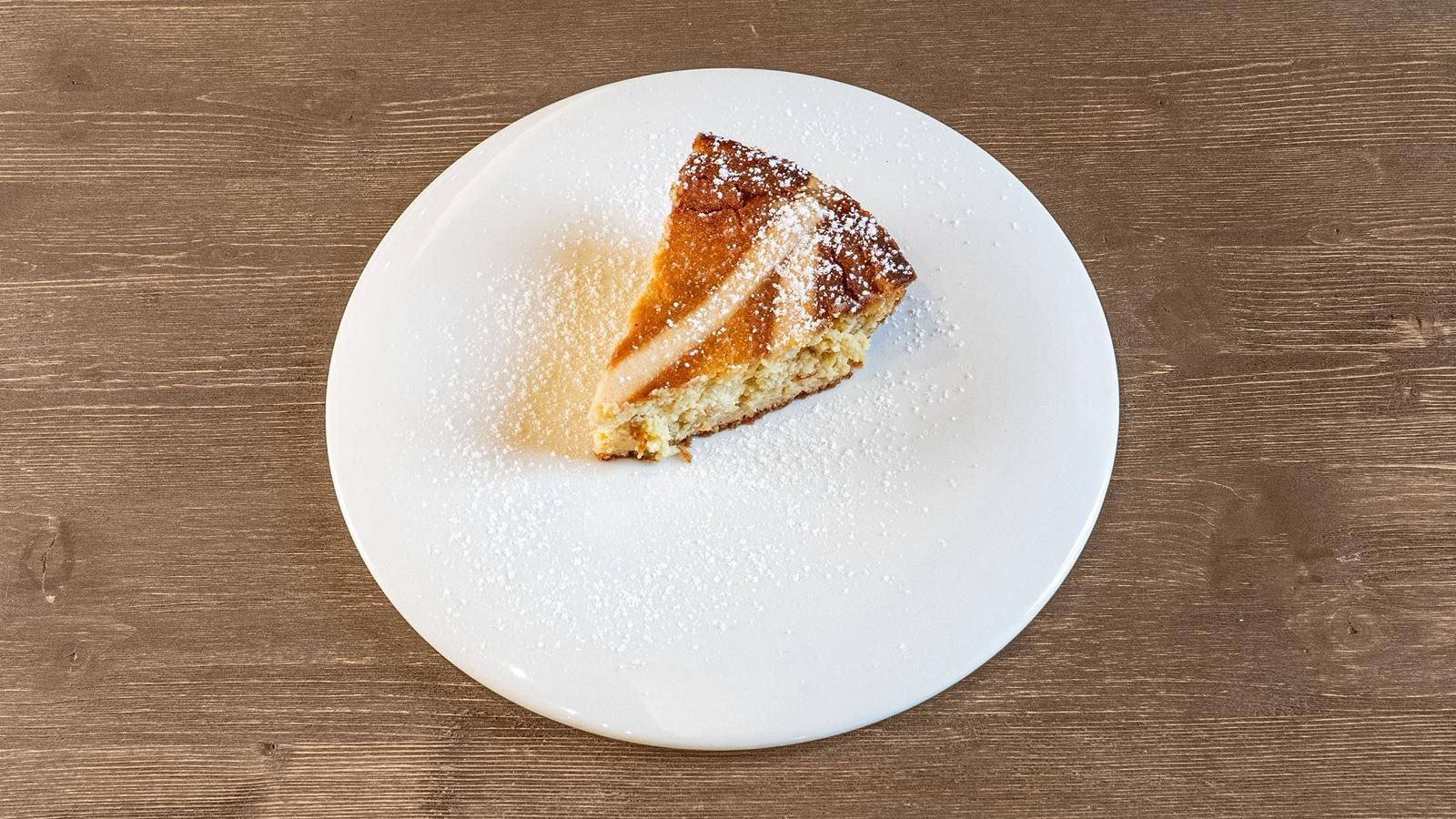 Fetta di torta su un piatto bianco su un tavolo di legno