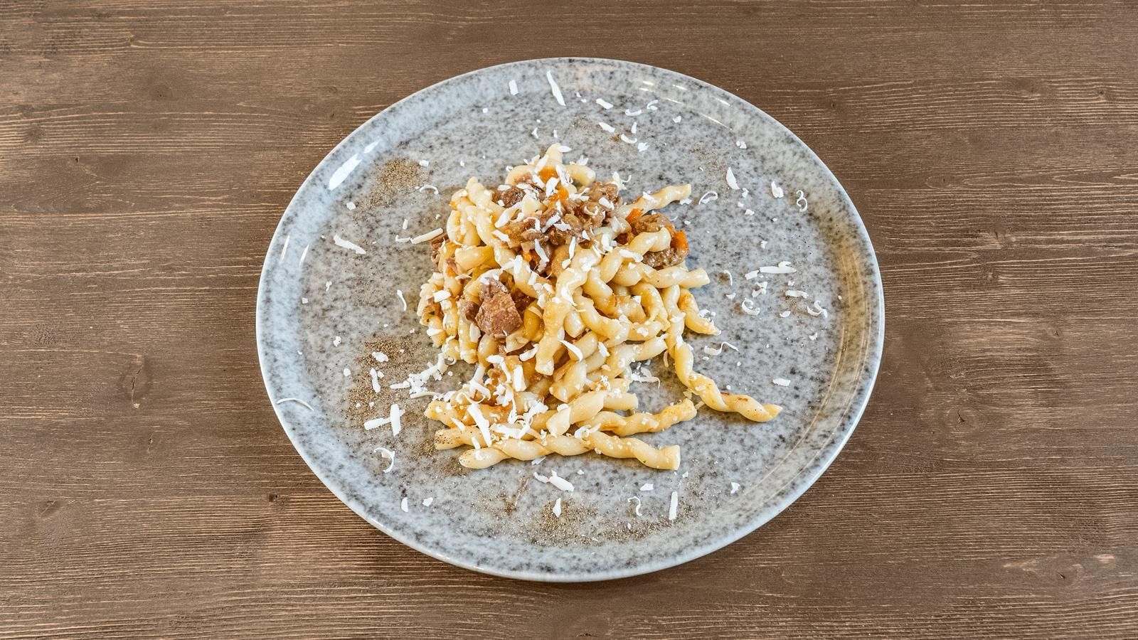 Un piatto di pasta cremosa con formaggio grattugiato su un tavolo di legno.