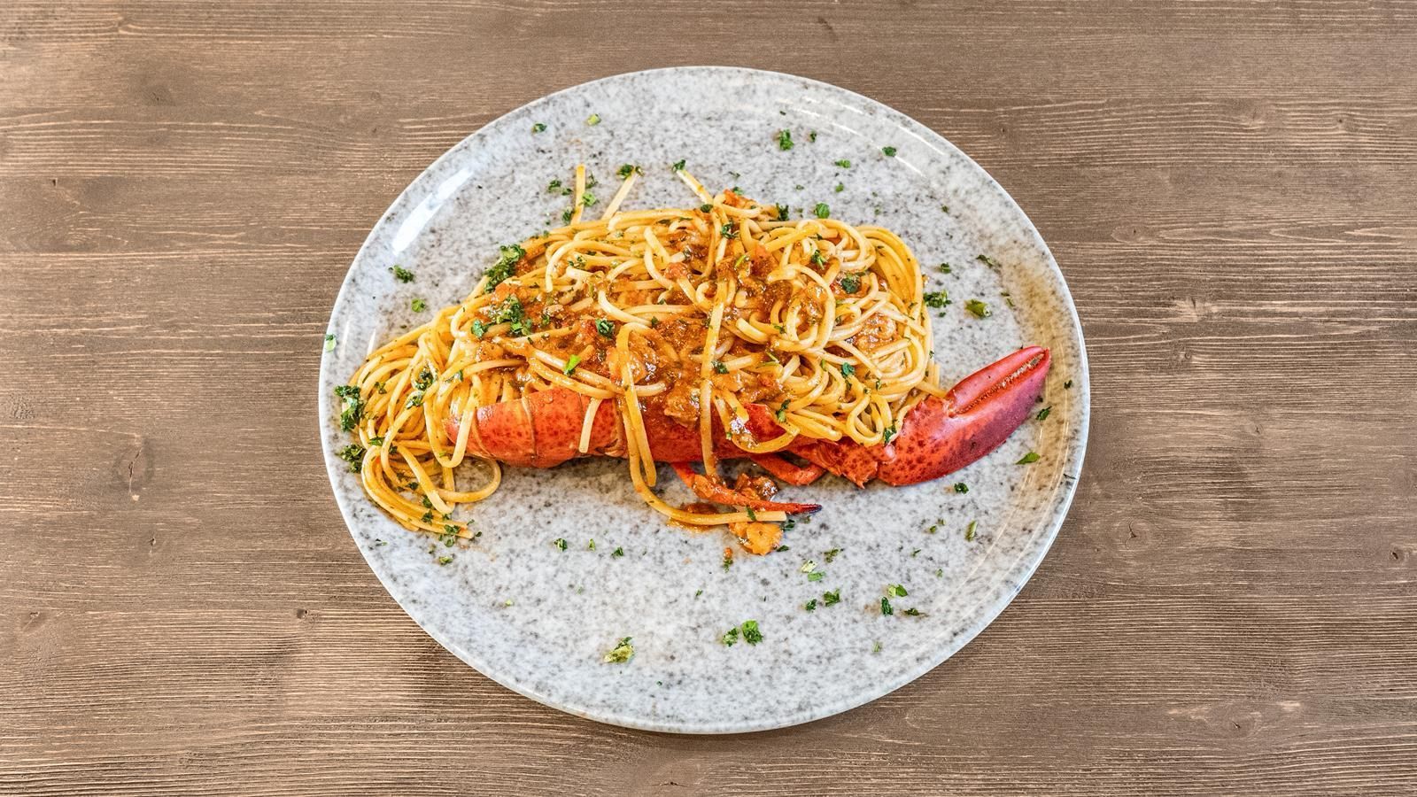 Piatto di pasta con gamberi ed erbe aromatiche su un rustico tavolo di legno