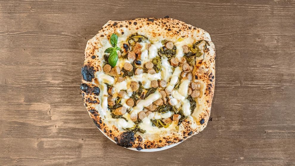 Pizza rotonda con verdure e salsa su un tavolo di legno