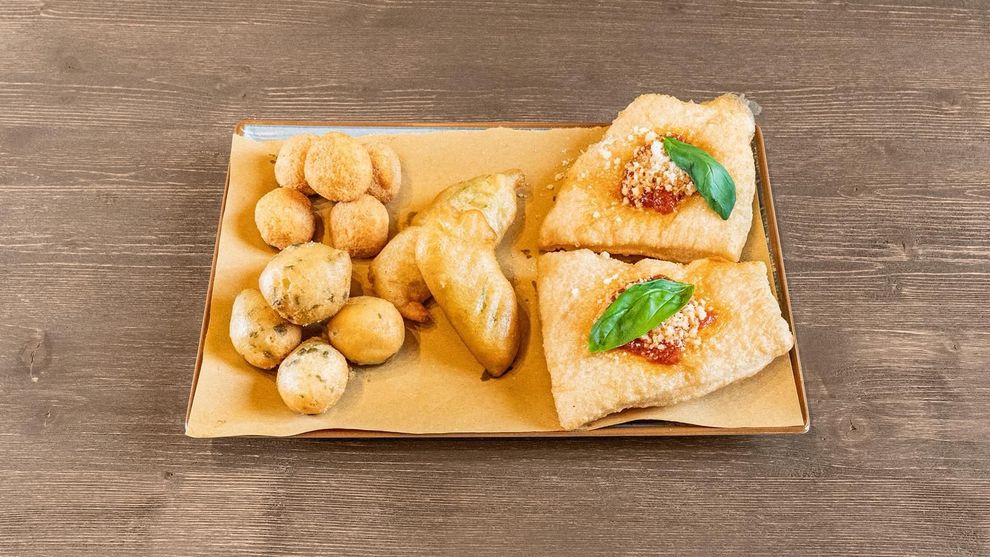 Piatto di pasticcini assortiti e bocconcini di pasta fritta su un tavolo di legno