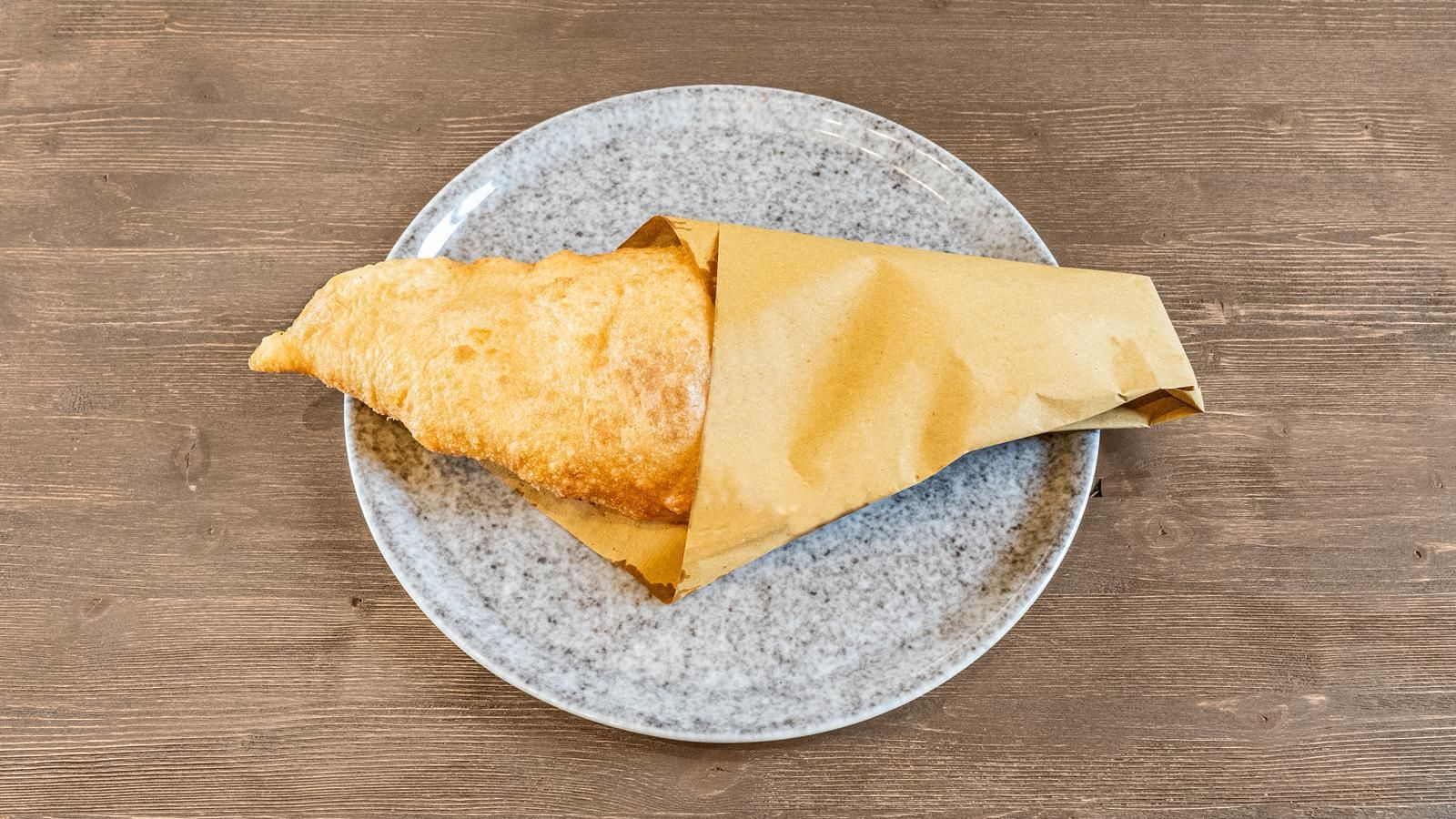 Pasta fritta dorata su un piatto screziato, su un tavolo di legno