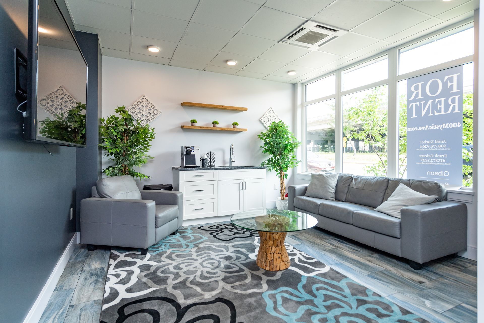 Modern office waiting area, gray furniture, floral rug, kitchenette, 