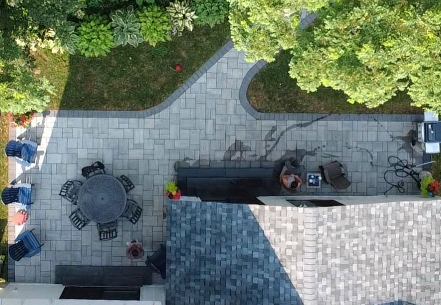 Overhead view of a patio with a table, chairs, paving stones, and greenery.