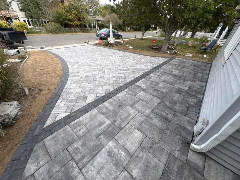Brick driveway with dark border, leading to street.