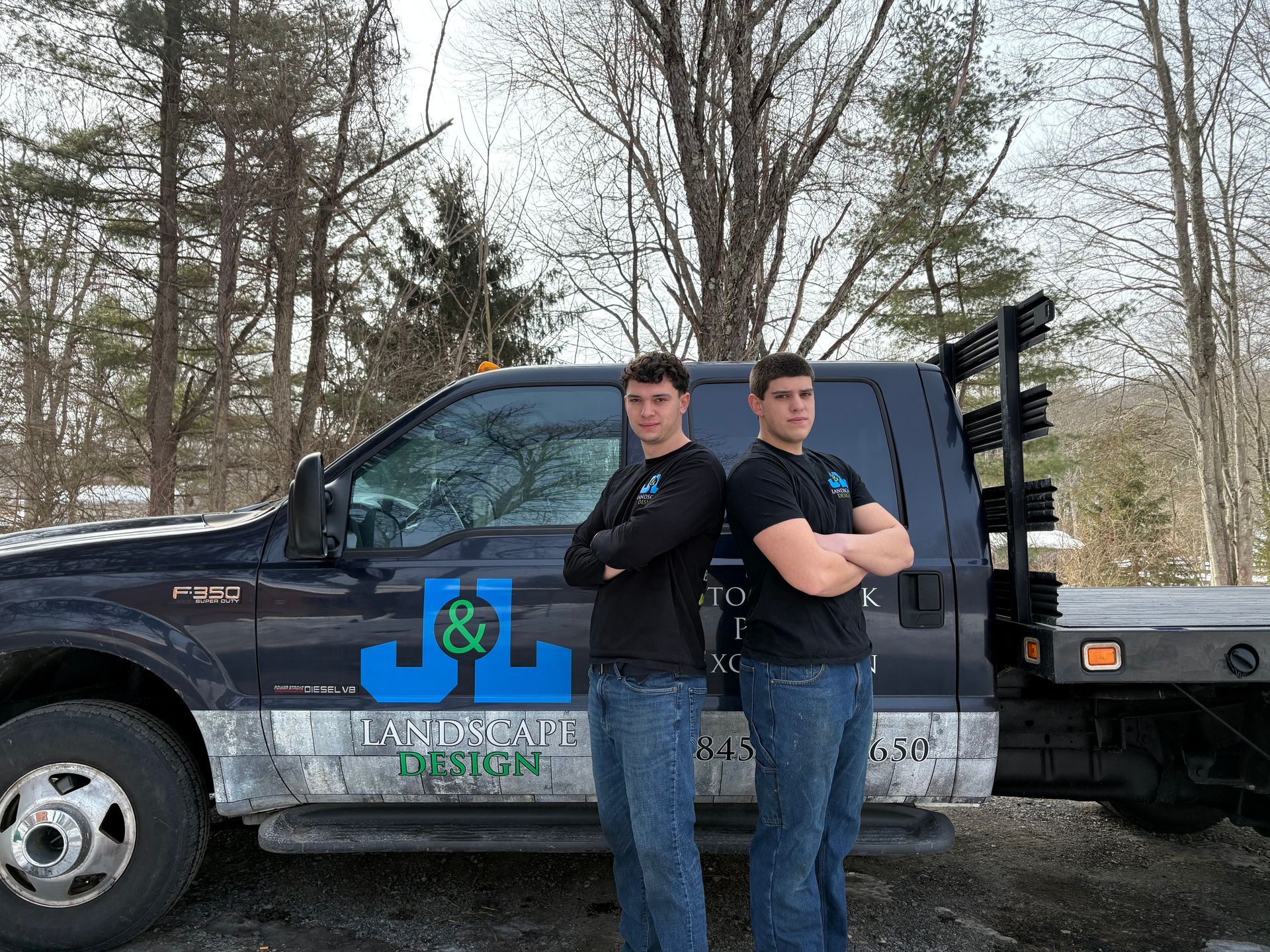 Two men stand with arms crossed next to a work truck with