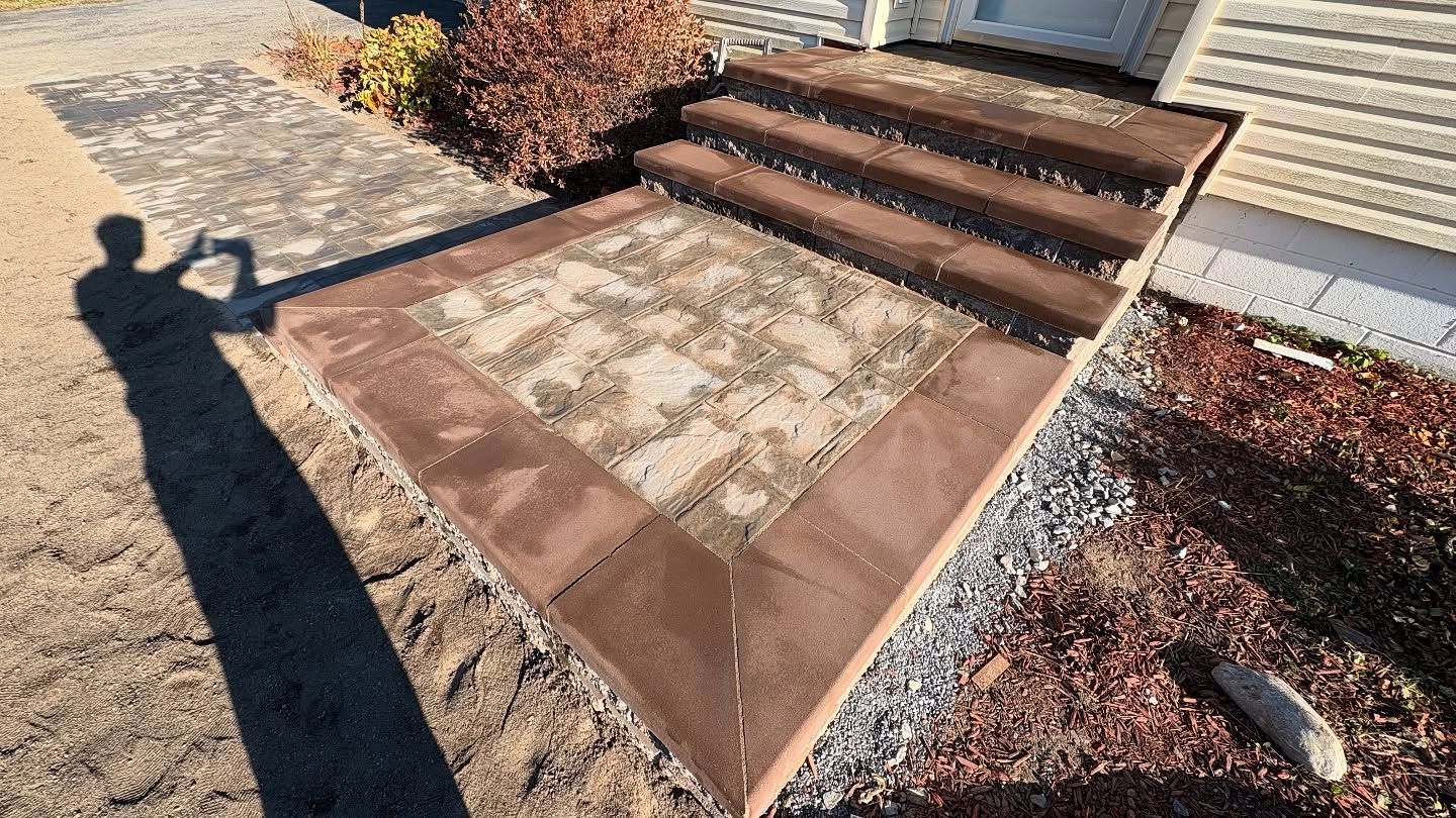 Stone steps leading up to a door. A person's shadow is visible on the walkway.